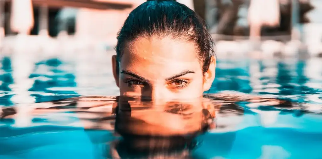 Mujer mirando con la cara semisumergida en el agua de una piscina