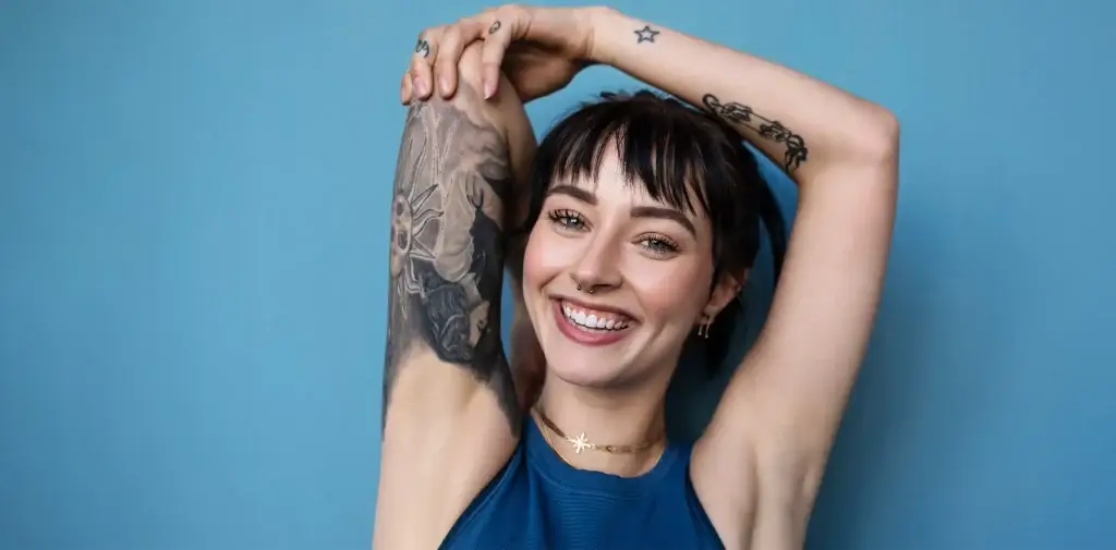 Mujer sonriendo y mostrando un tatuaje en el brazo
