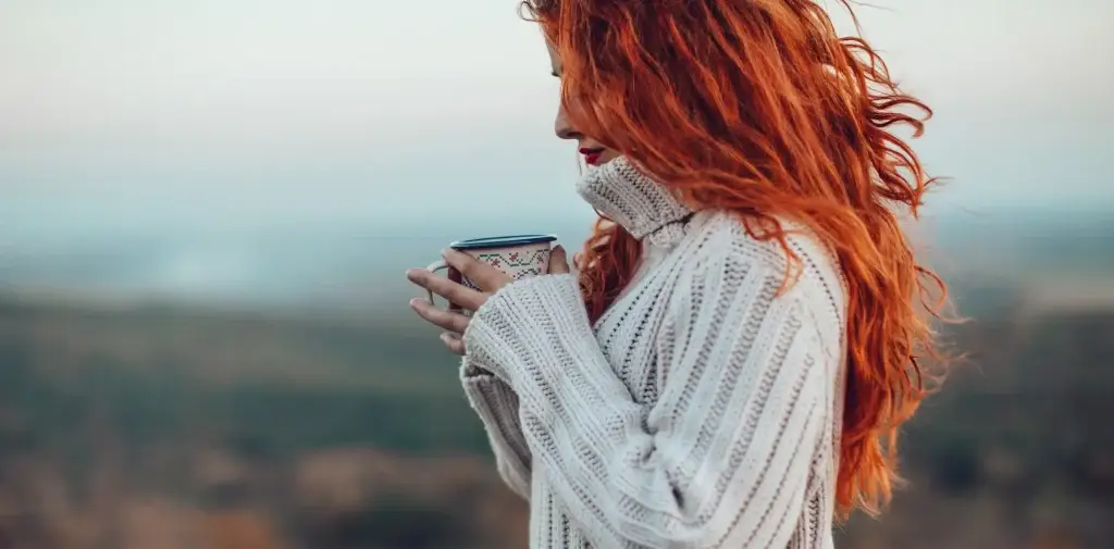 Mujer en el campo sosteniendo una taza