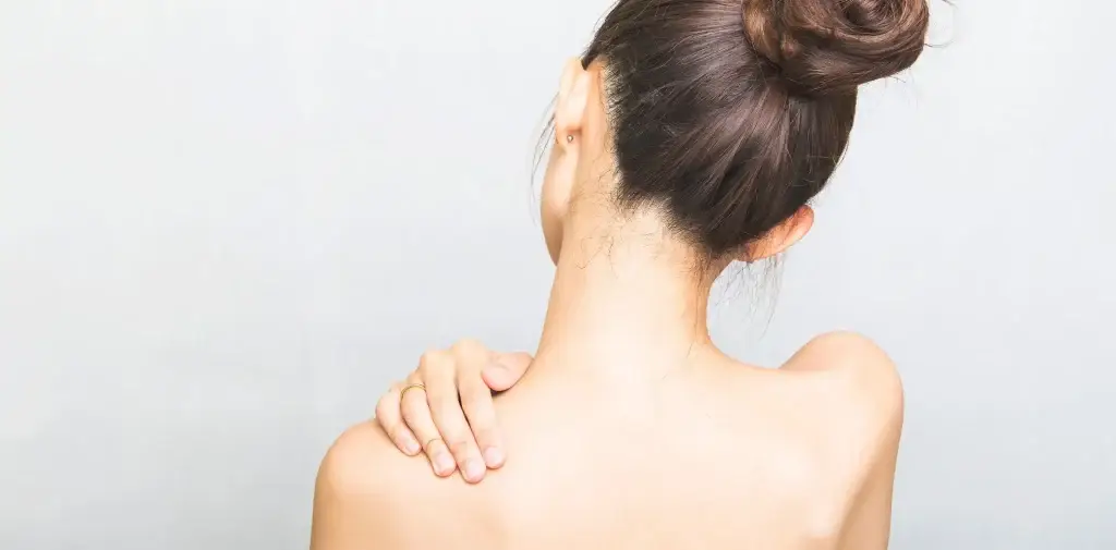 mujer de espaldas tocándose el hombro